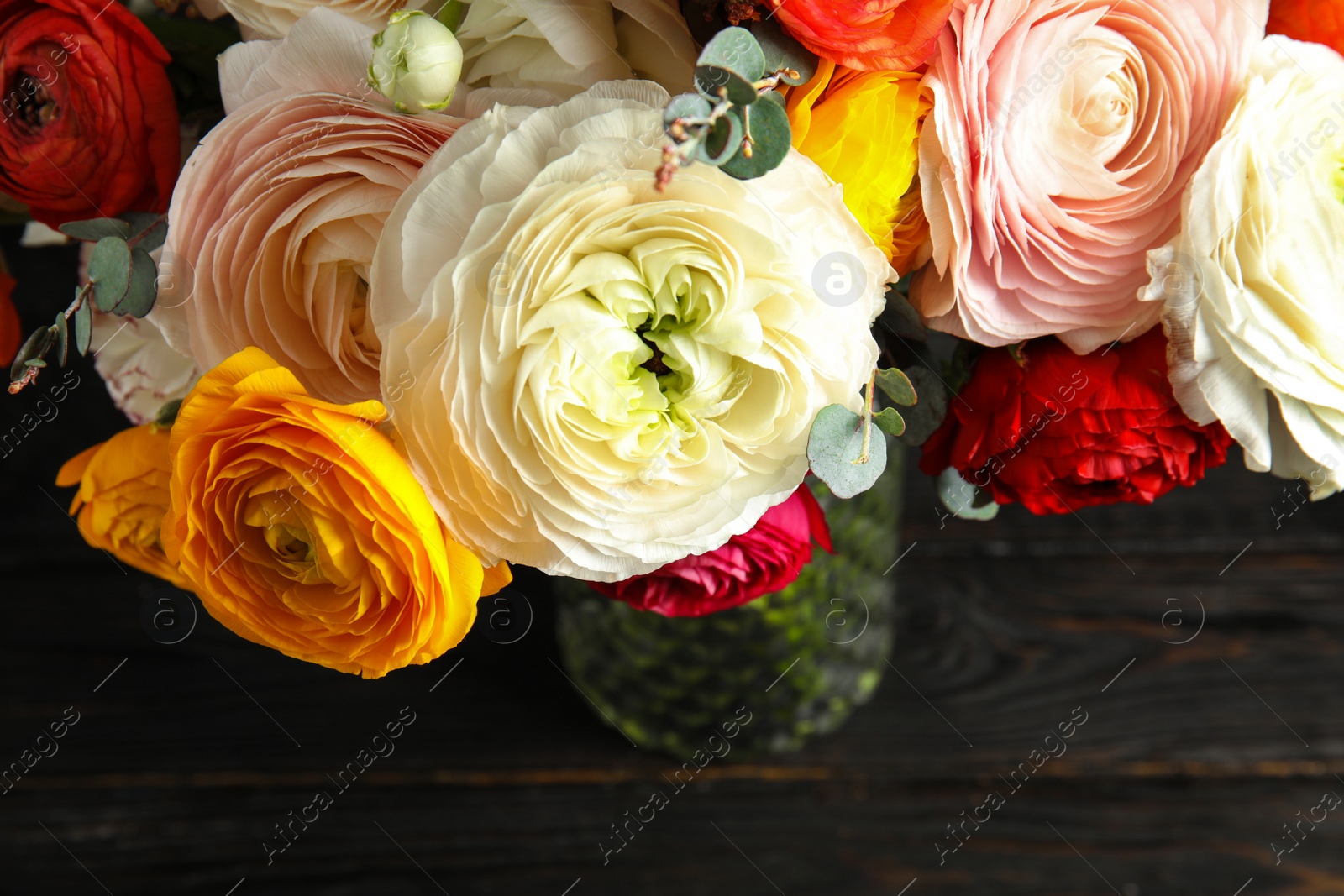 Photo of Bouquet with beautiful bright ranunculus flowers on dark table, view from above