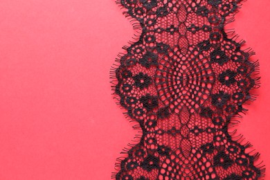 Black lace on red background, top view. Space for text