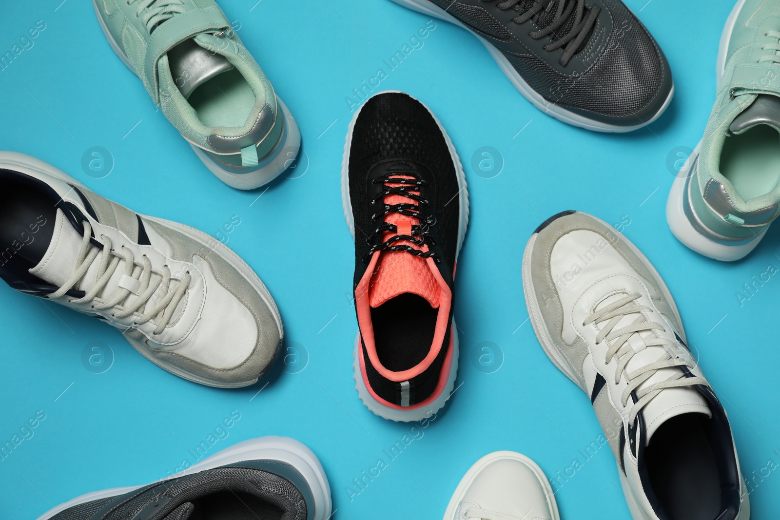 Photo of Different stylish sport shoes on light blue background, flat lay