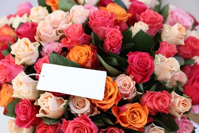 Photo of Bouquet of beautiful roses with blank card, closeup