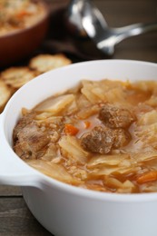 Tasty cabbage soup with meat and carrot on wooden table, closeup