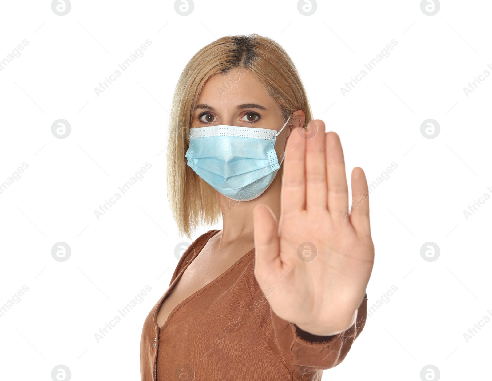 Photo of Woman in protective mask showing stop gesture on white background. Prevent spreading of coronavirus