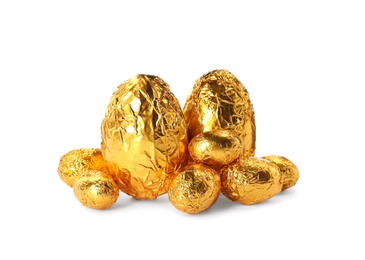 Chocolate eggs wrapped in golden foil on white background