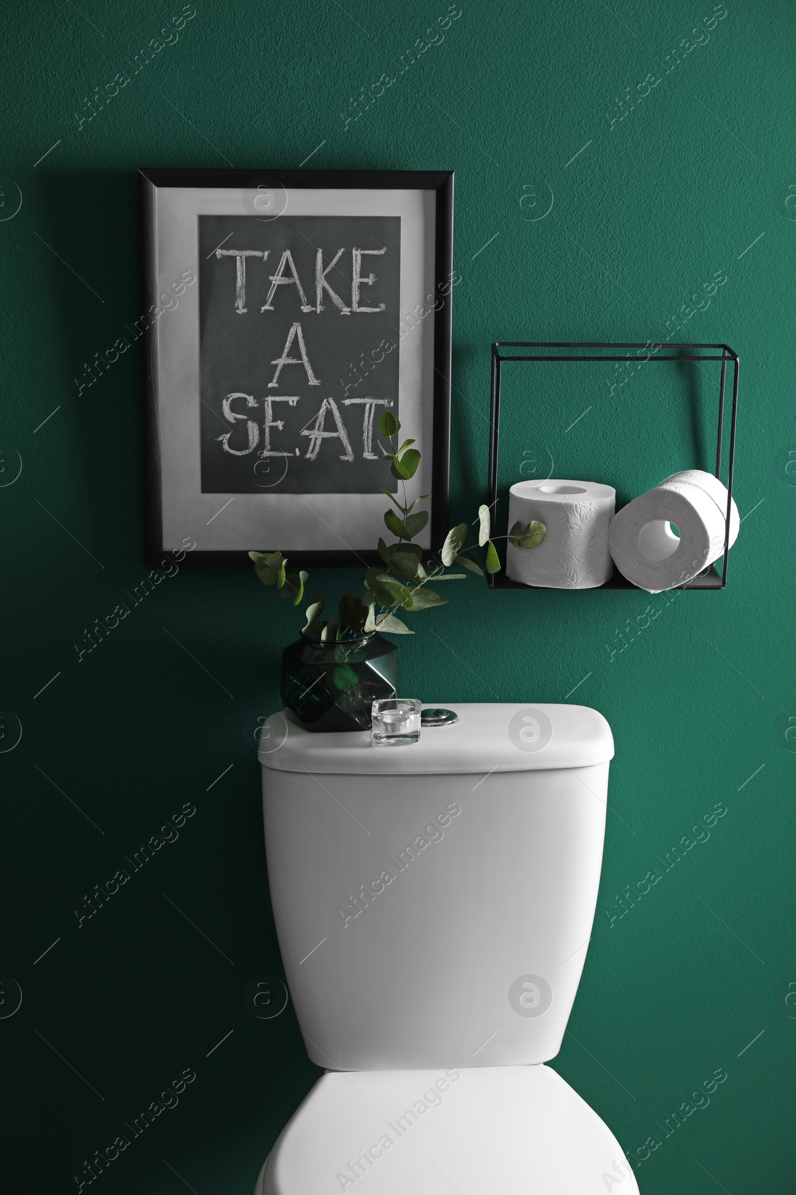 Photo of Decor elements, paper rolls and toilet bowl near green wall. Bathroom interior