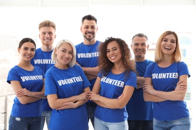 Team of volunteers in uniform on light background