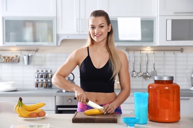 Photo of Young woman preparing protein shake at table in kitchen