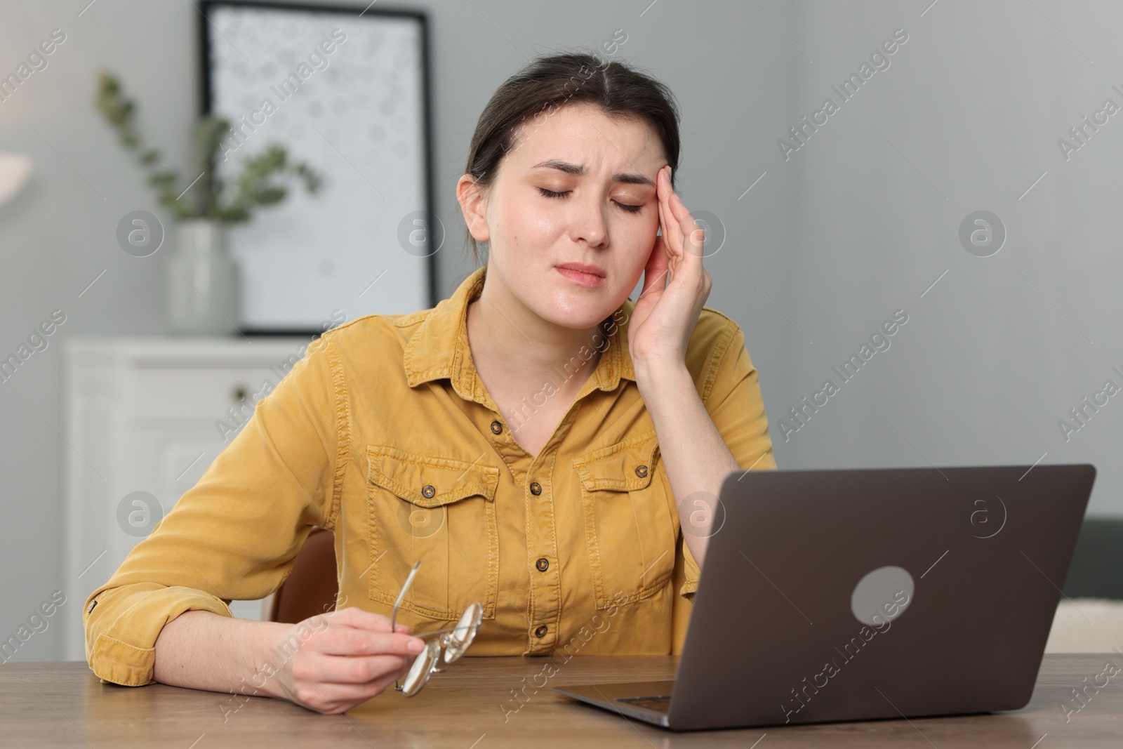 Photo of Overwhelmed woman sitting with laptop at table indoors