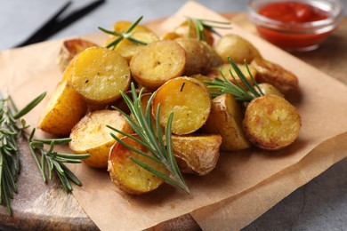 Photo of Tasty baked potato and aromatic rosemary on wooden board, closeup