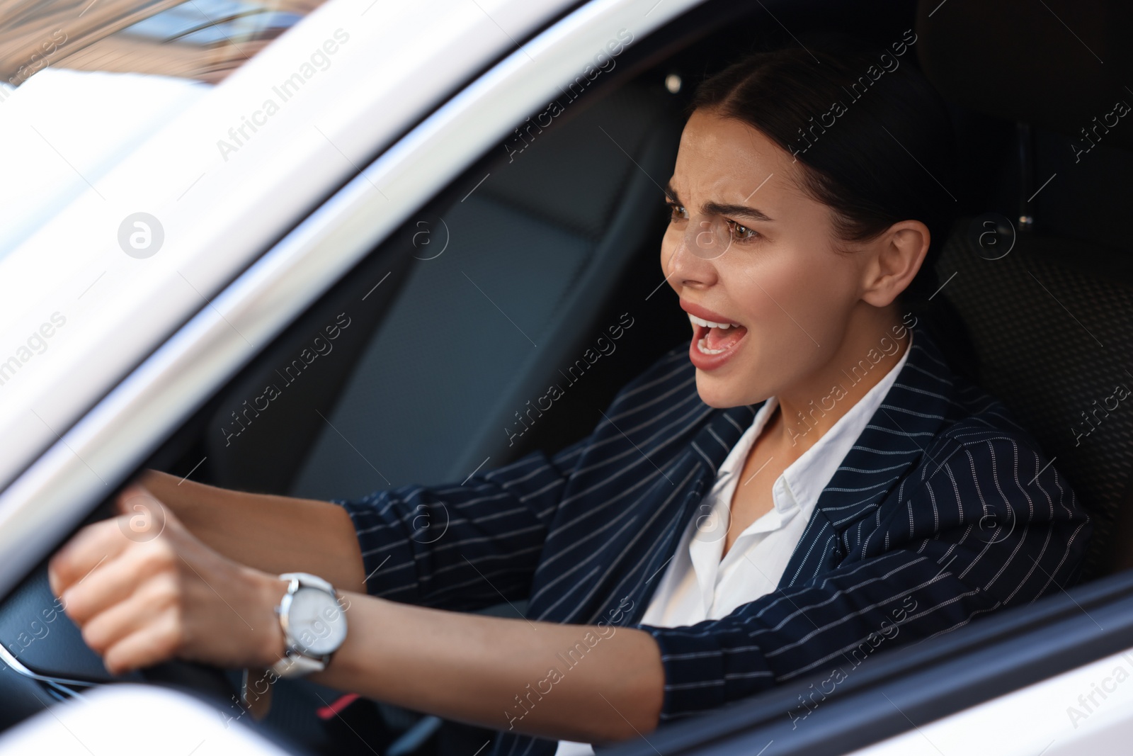 Photo of Angry driver screaming in her car, view from outside. Stuck in traffic jam