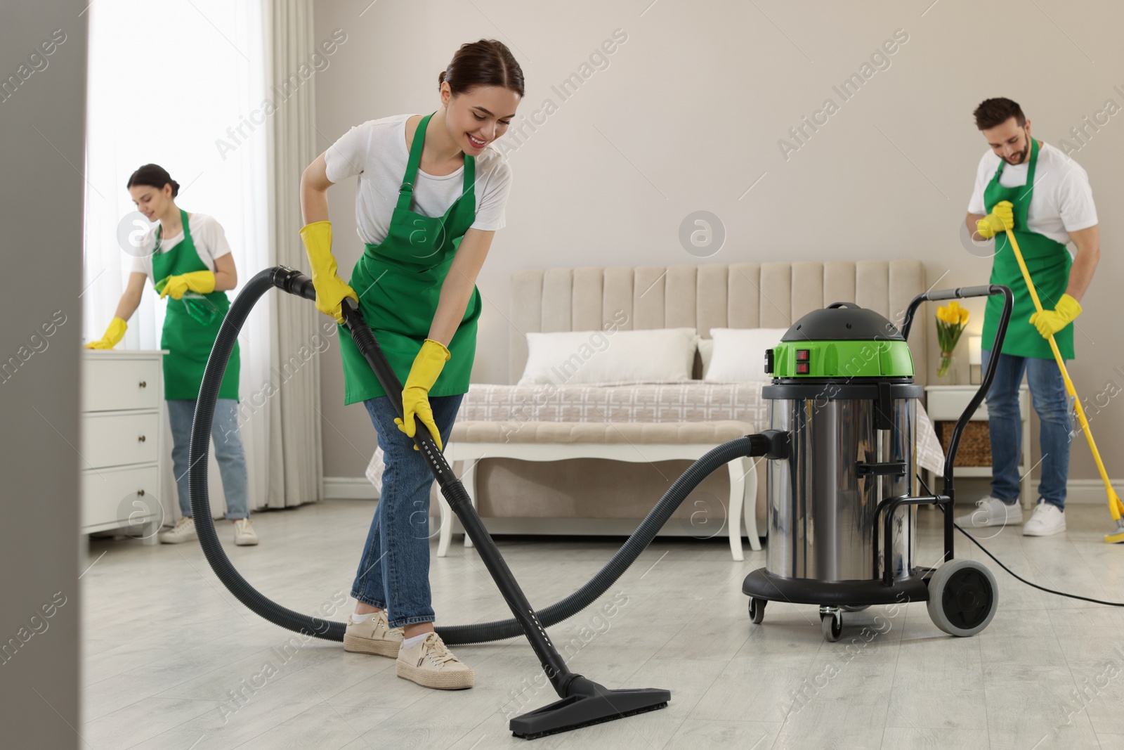 Photo of Team of professional janitors working in bedroom