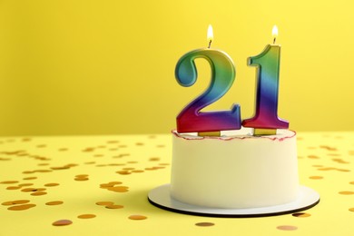 Photo of Coming of age party - 21st birthday. Delicious cake with number shaped candles on yellow background, space for text