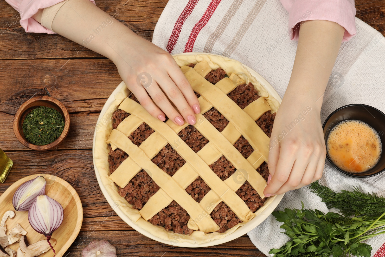 Photo of Woman making lattice top for meat pie at wooden table, top view