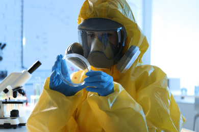 Scientist in chemical protective suit with Petri dish at laboratory. Virus research