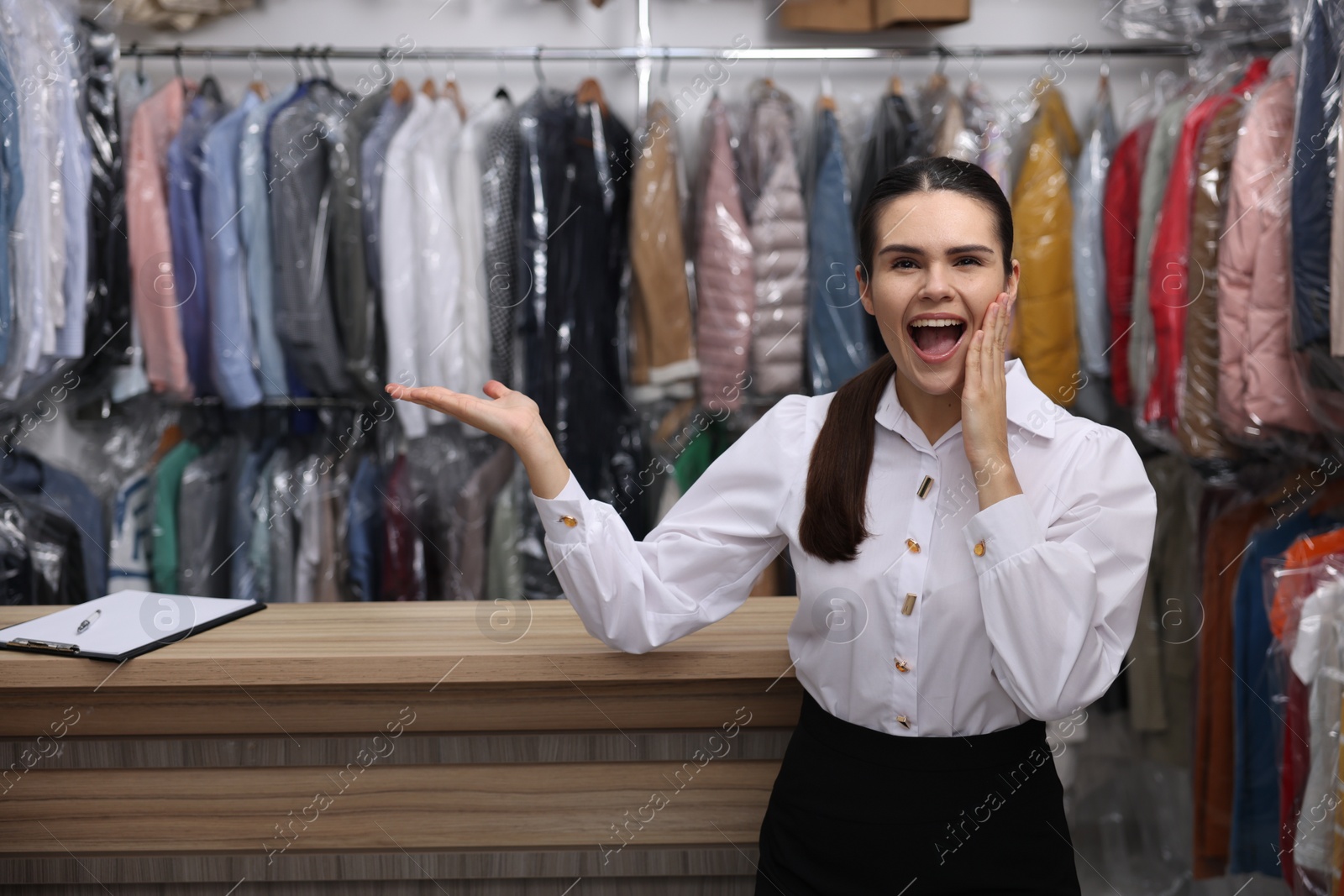 Photo of Dry-cleaning service. Emotional worker near counter indoors, space for text