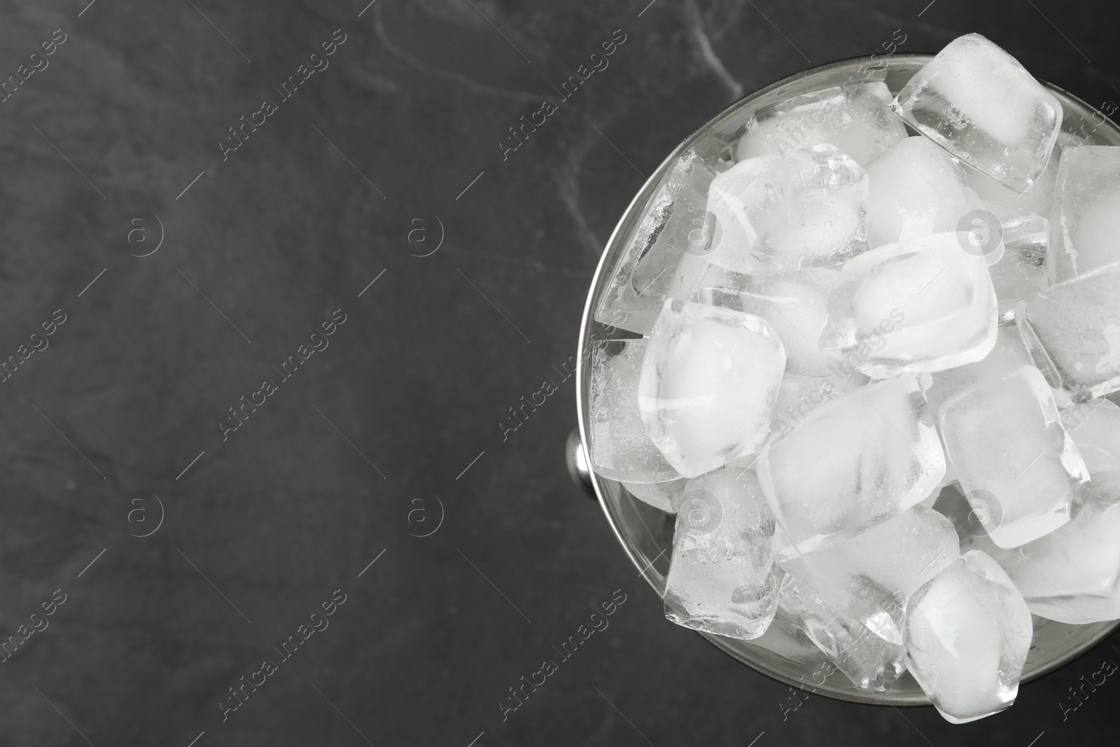 Photo of Metal bucket with ice cubes on grey background, top view. Space for text