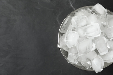 Metal bucket with ice cubes on grey background, top view. Space for text