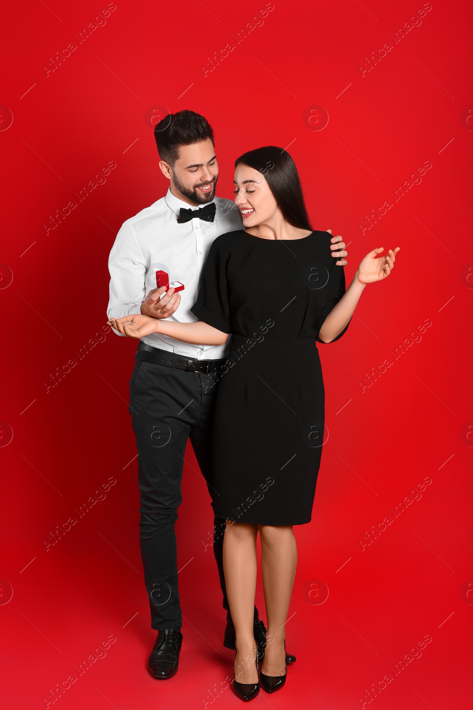 Photo of Man with engagement ring making marriage proposal to girlfriend on red background