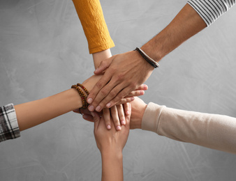 Photo of People holding hands together over grey stone background, top view. Unity concept