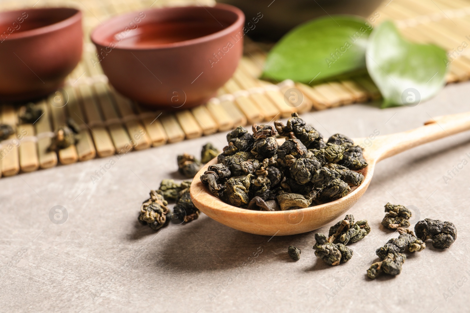 Photo of Composition with spoon of Tie Guan Yin Oolong tea and brewed beverage on grey table