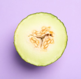 Photo of Half of ripe tasty melon on violet background, top view