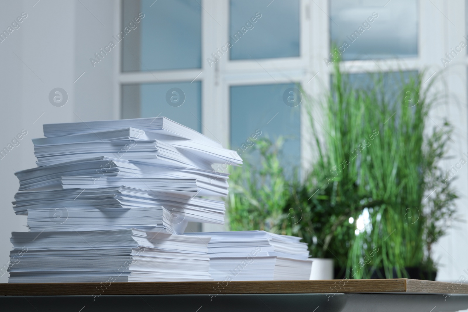 Photo of Stack of paper sheets on wooden table indoors. Space for text