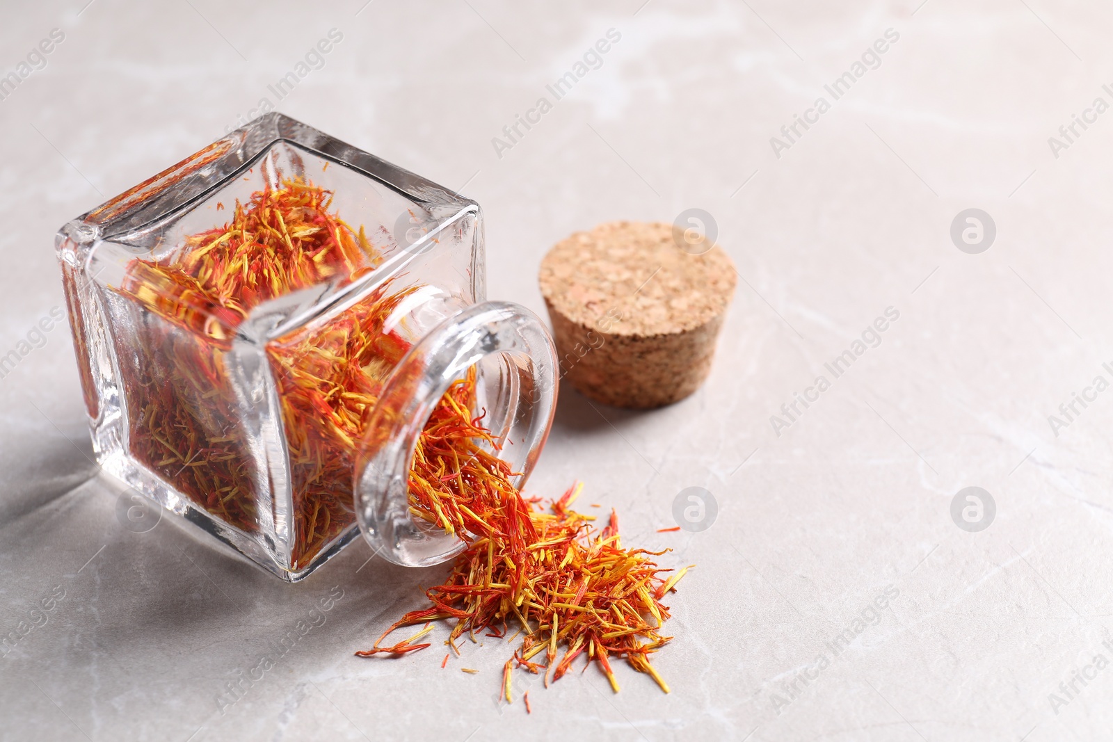 Photo of Aromatic saffron, glass jar and lid on light gray table, space for text