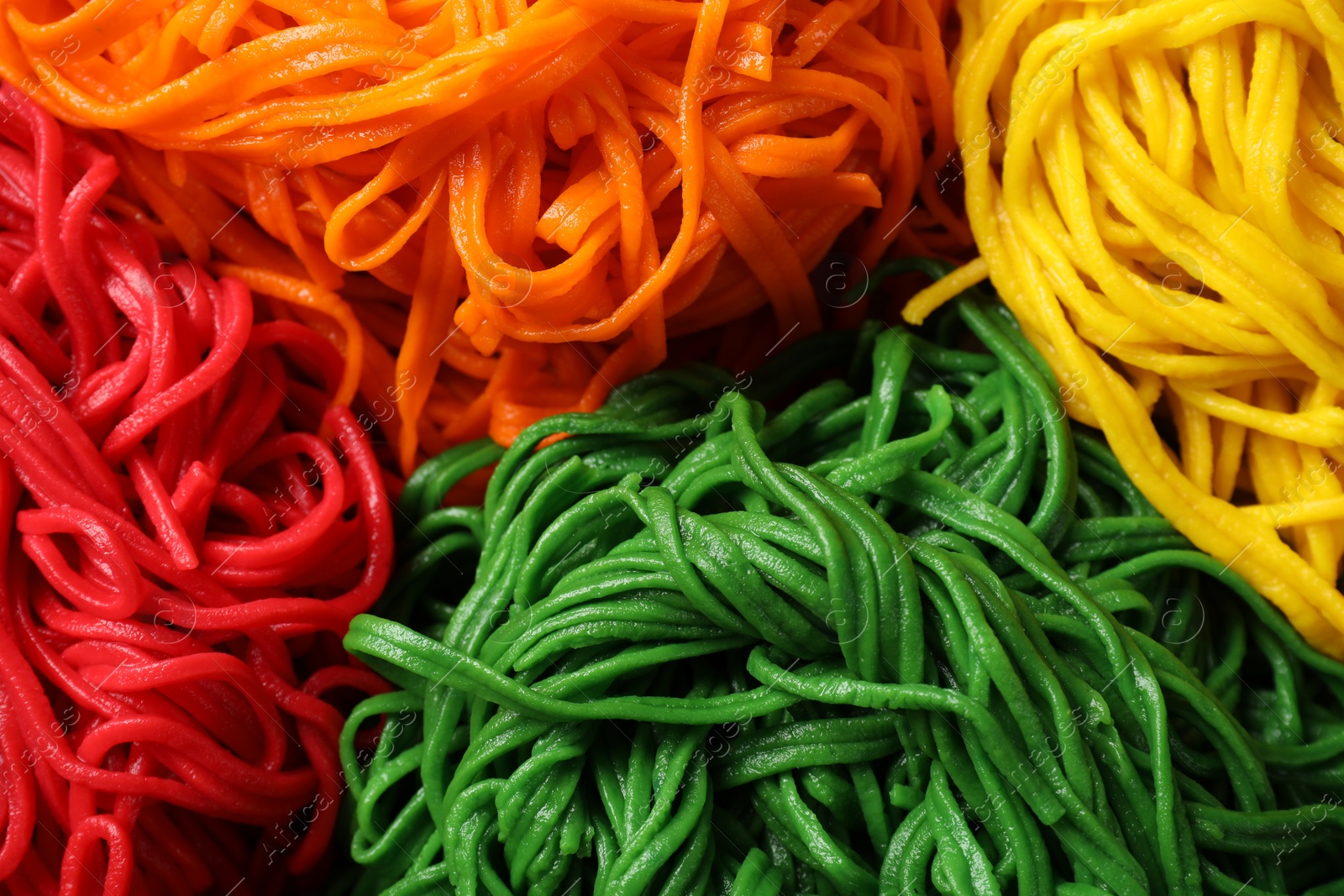 Photo of Rolled spaghetti painted with different food colorings as background, closeup