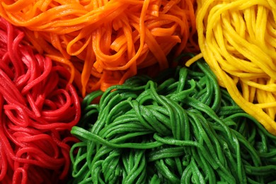 Photo of Rolled spaghetti painted with different food colorings as background, closeup