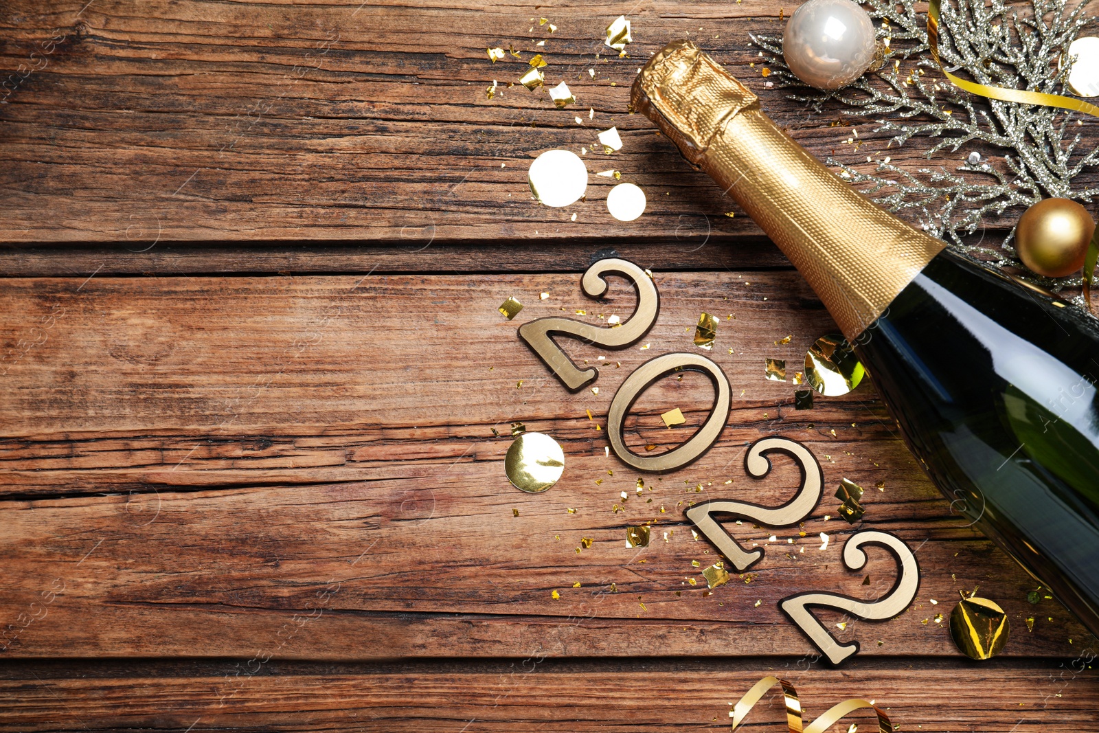 Photo of Happy New Year 2022! Flat lay composition with bottle of sparkling wine on wooden table, space for text