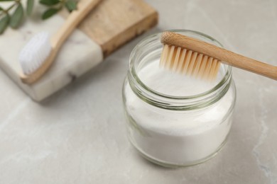 Photo of Bamboo toothbrush and jar of baking soda on light grey marble table