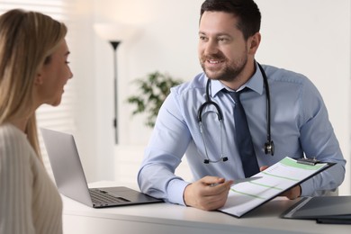 Professional doctor working with patient at white table in hospital