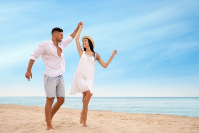 Photo of Lovely couple dancing on beach near sea. Space for text