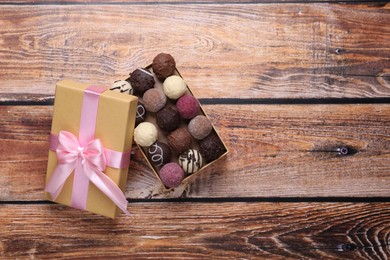 Photo of Open box with delicious chocolate candies on wooden table, top view. Space for text