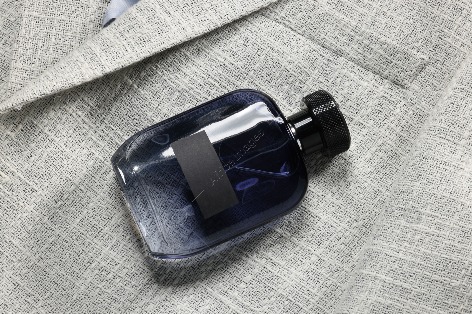Photo of Luxury men's perfume in bottle on grey jacket, top view