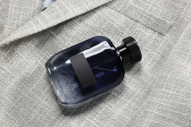 Luxury men's perfume in bottle on grey jacket, top view