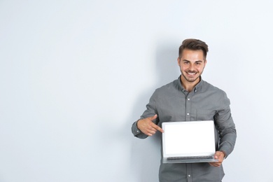 Photo of Man in casual clothes with laptop on light background