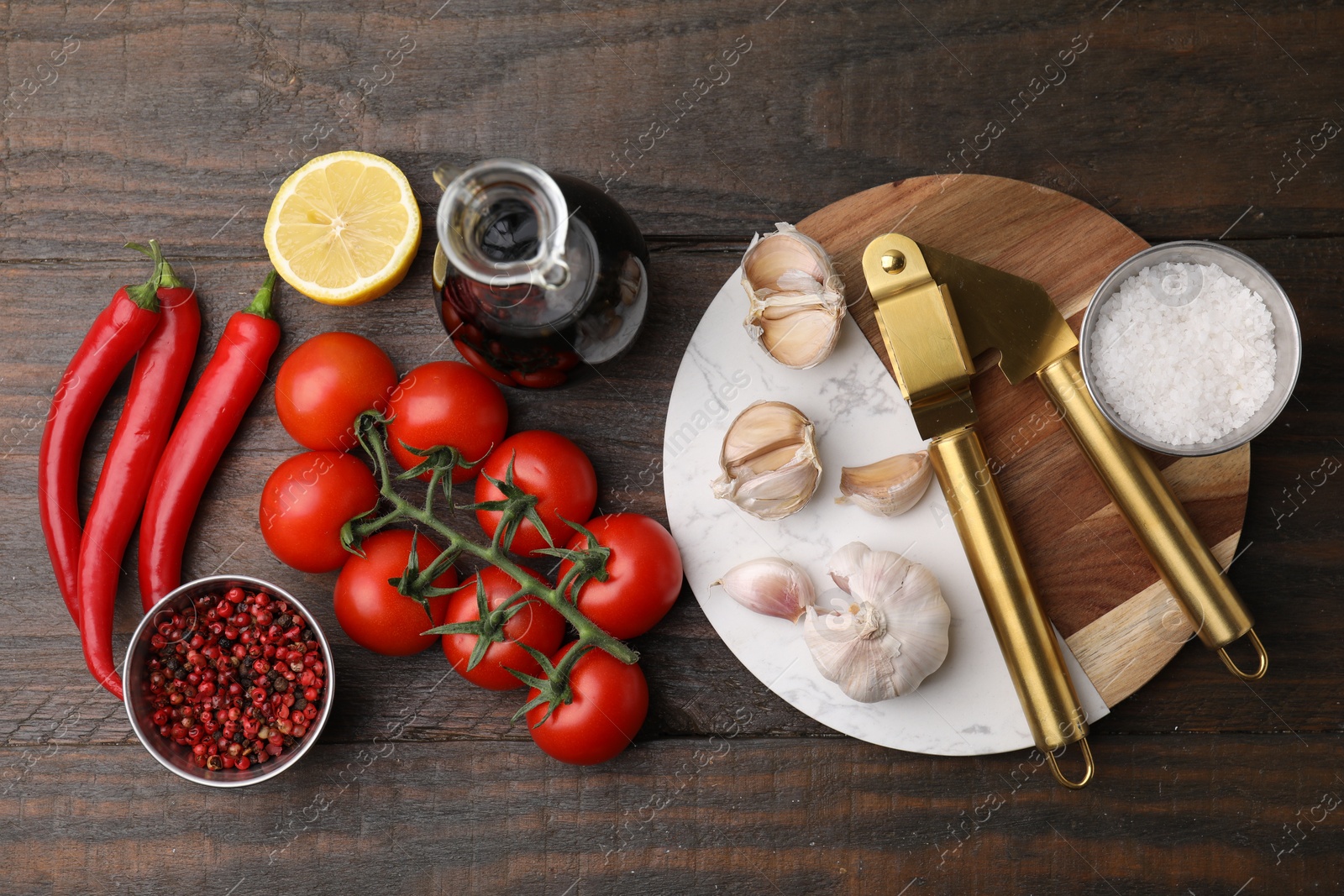 Photo of Different fresh ingredients for marinade and garlic press on wooden table, flat lay