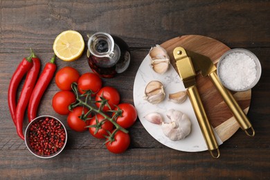 Photo of Different fresh ingredients for marinade and garlic press on wooden table, flat lay