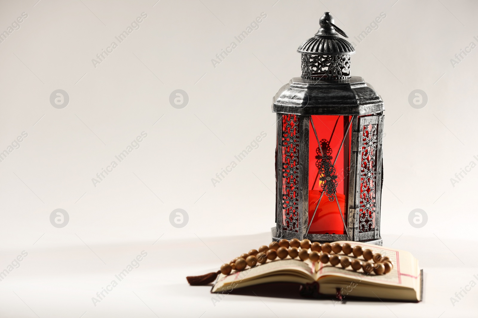 Photo of Arabic lantern, Quran and misbaha on light background. Space for text