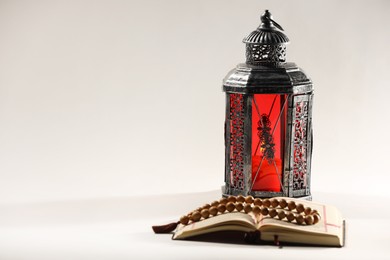 Photo of Arabic lantern, Quran and misbaha on light background. Space for text