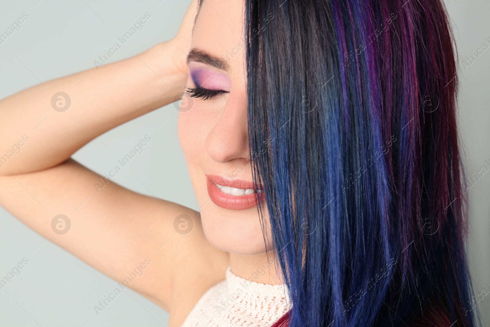 Photo of Young woman with bright dyed hair on light background, closeup