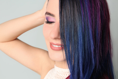 Photo of Young woman with bright dyed hair on light background, closeup