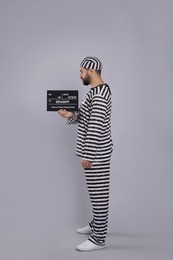 Photo of Prisoner in special uniform with mugshot letter board  
on grey background