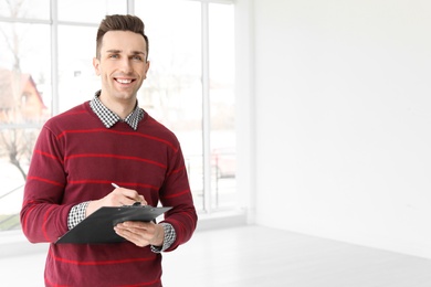 Photo of Male real estate agent with clipboard indoors