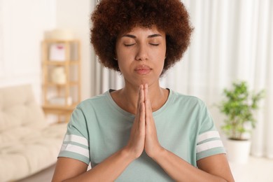 Photo of Woman with clasped hands praying to God indoors