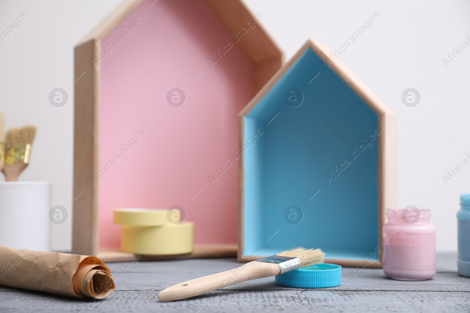 Photo of Brush with paint and wooden houses on grey table