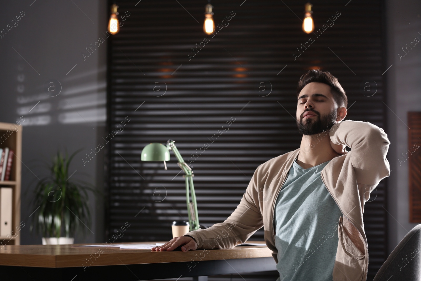 Photo of Man suffering from neck pain in office. Bad posture problem