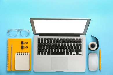 Photo of Laptop and office stationery on light blue background, flat lay