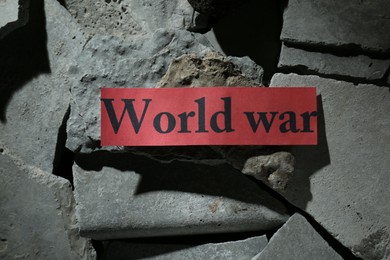 Photo of Paper with words World War on pieces of concrete, top view
