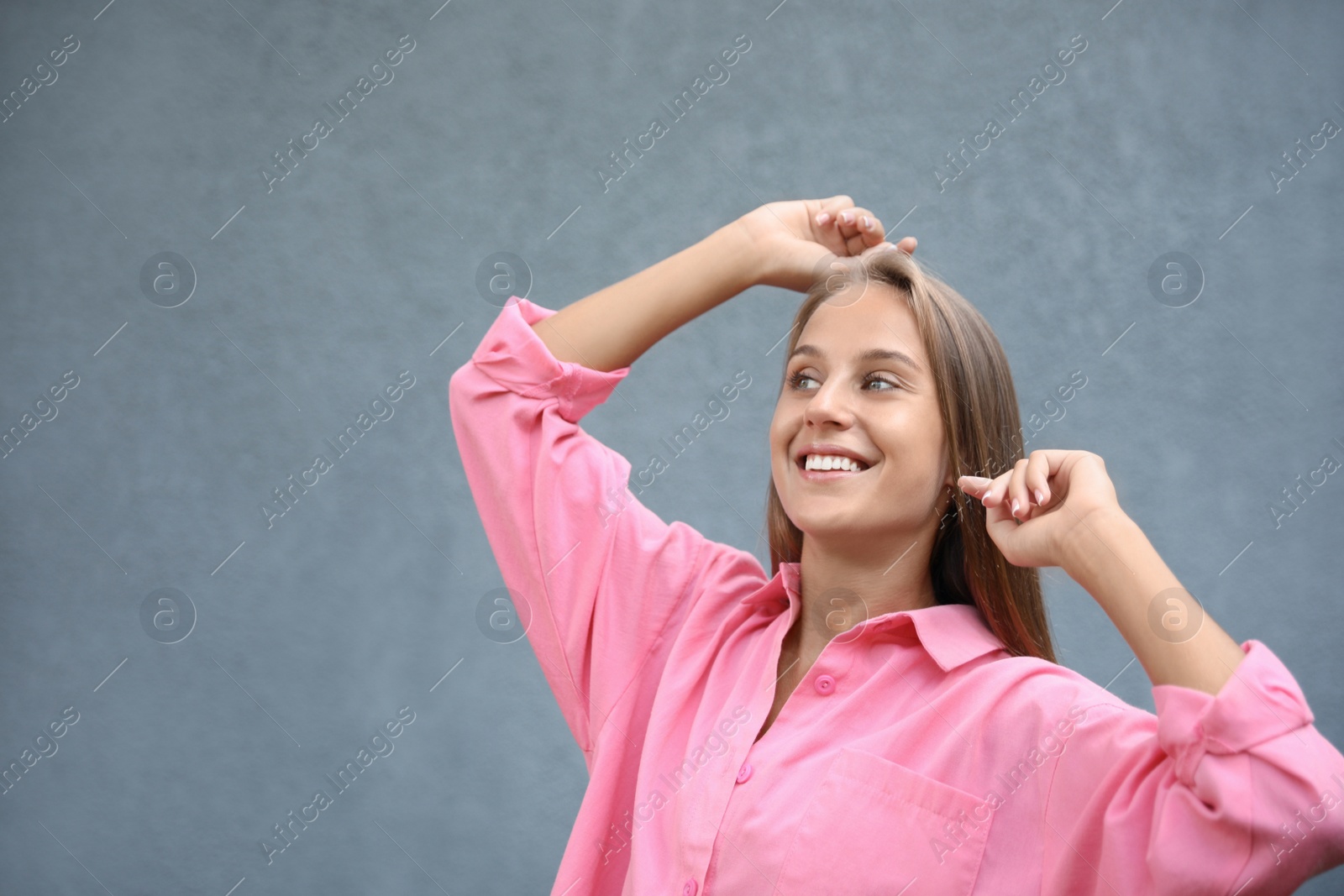 Photo of Beautiful young woman in stylish shirt near grey wall, space for text